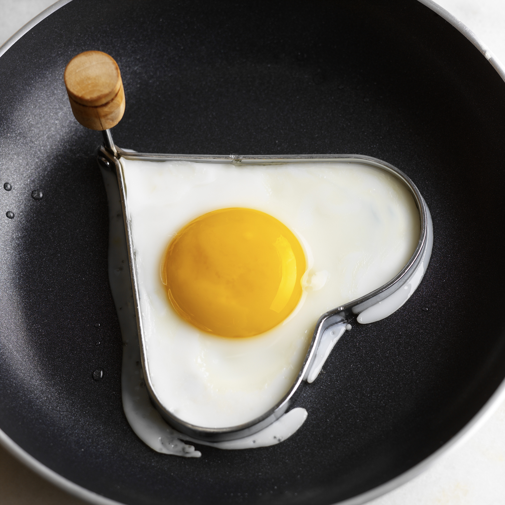 Heart-shaped egg in frying pan with mold