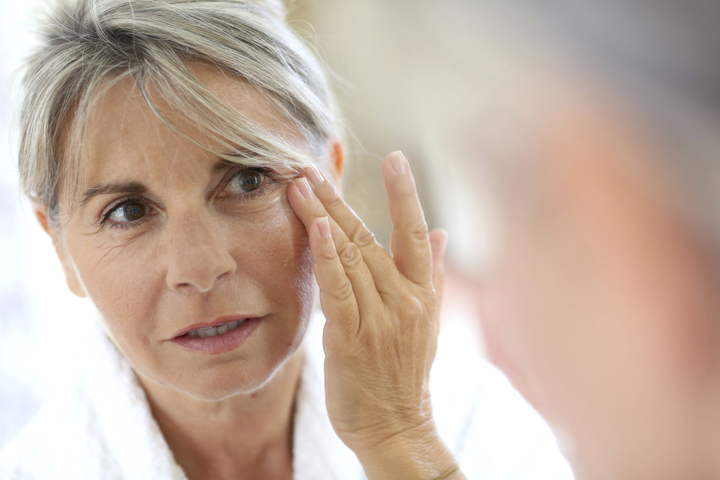 Middle-aged woman applying cream on face