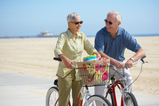 Couple posing on bikes at beach, California